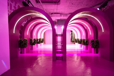 The vineyard installation invites guests to walk through pink tunnels decorated with grapevines.