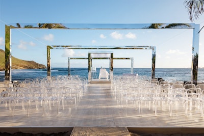 “We cheated perspective with an inwards-moving platform and a series of reflective arches that shrank progressively towards the horizon, making guests feel as if they were moving into the sea ahead. The contemporary chuppah was simple and sleek, taking advantage of the gorgeous St. Barth’s scenery by reflecting the beach, and the use of clear chairs kept the ceremony open, airy, and light.' Pictured: Private wedding in St. Barth’s