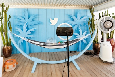 A photo booth invited guests to lie in a hammock with beach-theme props, against a blue backdrop with palm tree cutouts and the Twitter logo.