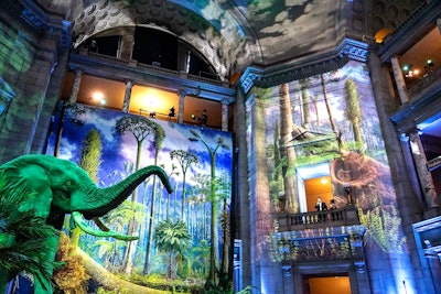Vivid projections and a printed mural transformed the rotunda space, recalling an ancient ecosystem. They framed a doorway and balcony from which speakers addressed the guests.