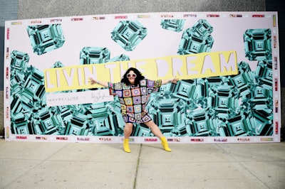 Here, Longshore poses in front of her outdoor mural for Maybelline. Longshore also appeared at Christian Siriano's show. As models strode around her, the artist worked on portraits of Frida Kahlo, Laverne Cox, and others.