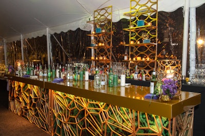 Guests could order cocktails at jewel-toned bars in the dinner tent. Purple cocktail napkins, candles, and flowers in golden vases spruced up the bars.