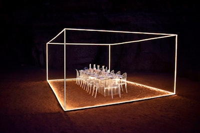 The illuminated steel structure measured almost 15 feet wide, 20 feet long, and eight feet high, with a transparent table set for 14 in the center. The LED lights strung along the frame lit the space for the evening.