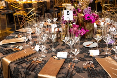 'To maintain that black-tie feel, we went with a black and gold color palette and worked luxurious colors like fuchsia, mulberry, and lavender into our florals—which also included gold painted leaves and textured vases to bring that additional sparkle to the room,' explained Cortellini. Rentals came from Standard Party Rentals, Bright Event Rentals, and Theoni Collection, while La Tavola Fine Linen provided linens.