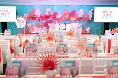 The conference space featured laser-cut palms in coral tones against a backdrop of aqua muslin, and custom table runners carried over the palm design. Florabella Studios designed the room's look.