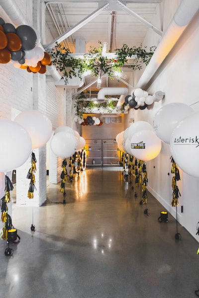 An Instagram-worthy entrance included both branded and gathered balloons, greenery along the ceiling, and oversize marquee numbers that read 50.