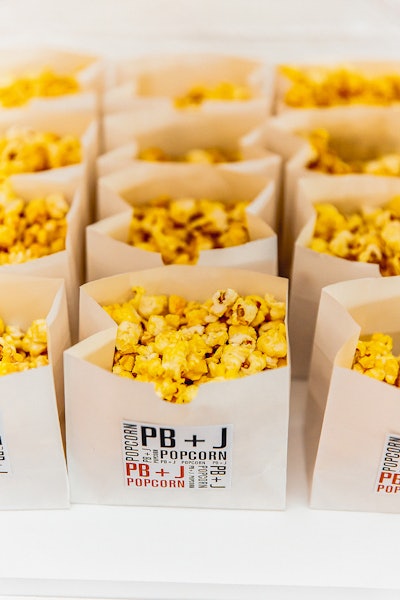 Popcorn bags with branded stickers are a hot item with clients, and Occasions Catering usually fills them with chips, popcorn, or root veggie chips. PB&J popcorn helped with the yellow-gold decor of the evening.
