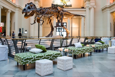 For a private corporate event held at the Field Museum in Chicago, corporate event designer David Epstein of HMR Designs opted for a green color scheme to pop against the venue's otherwise neutral backdrop, mixing printed green couches and textured greenery with a clean white and dark wood accents for added contrast.