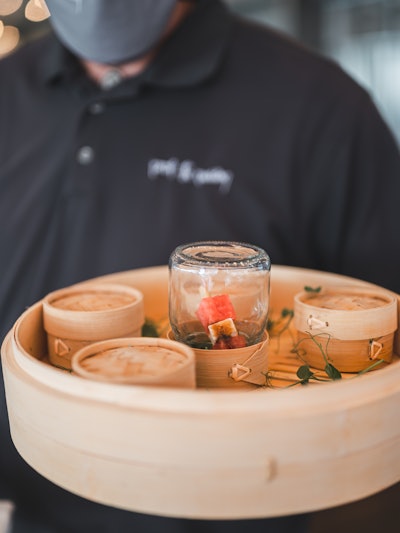 Juice Studios got creative, refusing to sacrifice passed hors d’oeuvres. Servers wore gloves and masks, displaying the appetizer option beneath the mason jar. Attendee portions were covered by wicker serving domes, ready to be enjoyed safely.