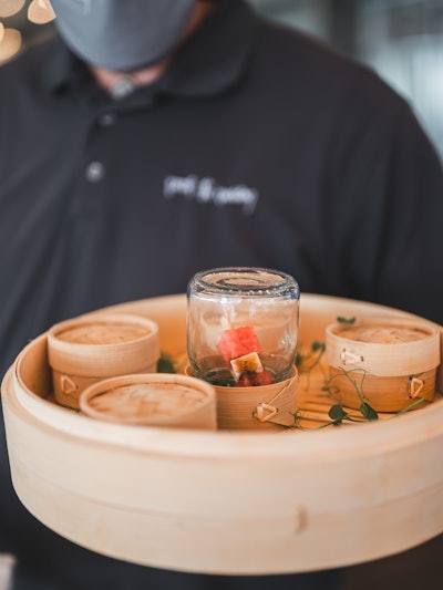 Juice Studios got creative, refusing to sacrifice passed hors d’oeuvres. Servers wore gloves and masks, displaying the appetizer option beneath the mason jar. Attendee portions were covered by wicker serving domes, ready to be enjoyed safely.