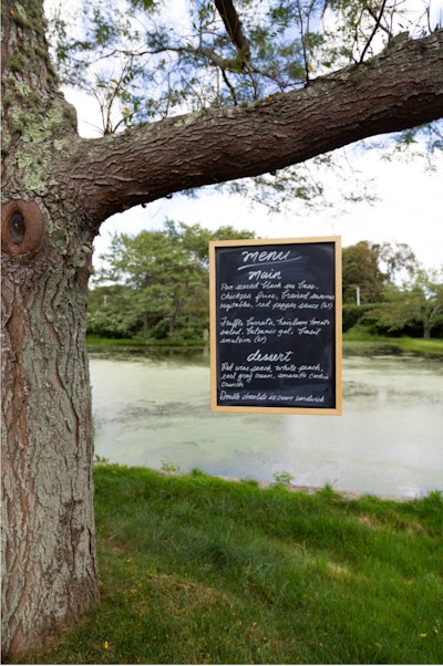 The event's menu was cleverly displayed from a nearby tree. Guests dined on a three-course meal from Olivier Cheng Catering & Events. To start, guests were served end-of-summer chilled corn soup with sage and duck prosciutto crisp. The main course consisted of two entrees: pan-seared black sea bass with chickpea fries, braised summer vegetables, and a red pepper sauce; and truffle burrata paired with heirloom tomato salad, balsamic gel, and basil emulsion. And for dessert, the Olivier Cheng team brought out a medley of red-wine peach, white peach, earl-grey cream, and amaretto cookie crunch; and a double-chocolate ice-cream sandwich.