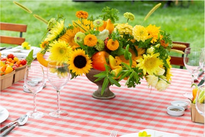 Farmer's market-inspired florals and decor took over the outdoor dining table that was reminiscent of an upscale picnic. Vibrant centerpieces were made up of signature summertime blooms—including sunflowers, gerbera daisies, carnations, and more—which were intermingled with red and yellow peppers for added color and creativity. Small baskets filled with fresh fruits and vegetables dotted the table, adding to the farmer's-market feel..