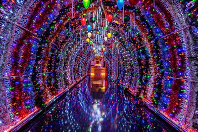 Guests enter the space through a reflective tunnel filled with colorful lights and ornaments, which opens into a holiday scene featuring a candy cane swing set, a giant Santa Claus, a Moët Champagne vending machine, and other fun details. Also on-site? A larger-than-life gingerbread replica of the resort.