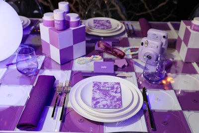 The event’s tablescape featured nods to the year 2000, including a tabletop made from empty CD cases plus candy necklaces and Polaroid cameras, all in the collection’s lavender and white color scheme.