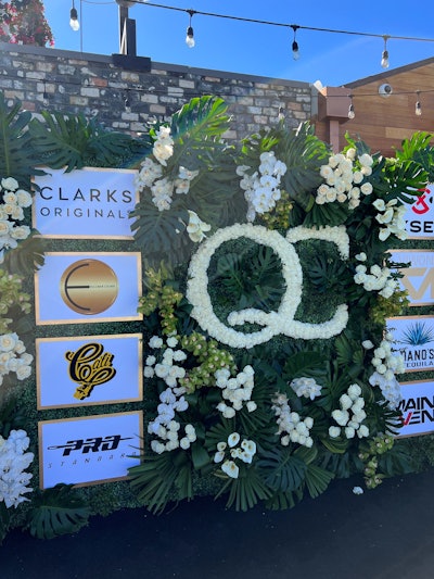 A botanical step-and-repeat included the QC logo spelled out in flowers.