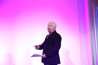 Guy Fieri gave a speech on a pink-hued stage at the Tribute Dinner.