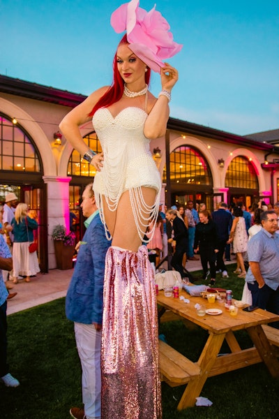 Aloni noted that the venue’s “old-world architecture” was photo-worthy and, with “the design of abundant pink floral arrangements and cabanas with flowing pink fabrics,” was the perfect nod to the rosy beverage. Another standout? Stilt-walkers donning pearls, blush floral hats, and glittered pink boots.