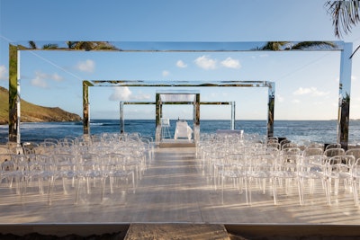 For a wedding in St. Barths, renowned designer Colin Cowie created a design that gradually drifted toward the horizon, with the aim of fooling perspective and making guests feel like they were stepping into the ocean. I created a series of shrinking reflective arches. Mirrored surfaces were also used in the chuppah to reflect the beach and surrounding scenery, and transparent chairs were chosen to keep the ceremony open, airy, and bright.