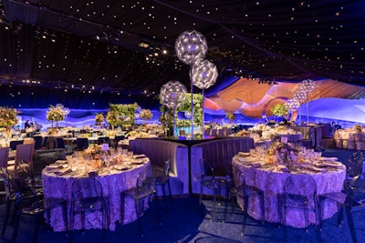At the symphony dinner, table settings featured a mix of organic and contemporary textiles, including raw linens partnered with mirror-topped tables and velvet banquettes accented by sequined overlays. On-theme centerpieces were composed of forest foliage and wildflowers adorned each dining table, while moss and vine-covered living walls served as the space's backdrop.
