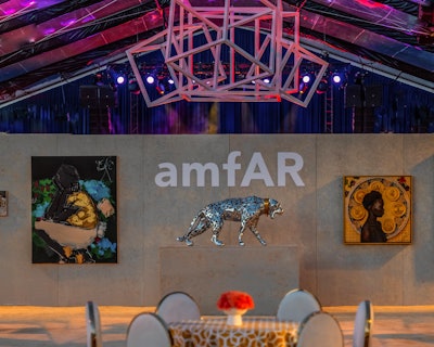 A 22-foot-long by 16-foot-wide by 11-foot-tall white cubical sculpture was suspended in the center of the dining and showroom tent. The hanging sculpture was designed to mimic the cubical pattern of the custom textile. Additional geometric shapes were used throughout the event space for dramatic effect and design continuity, and “intense lighting played a major role in bringing the space to life and transforming the environment throughout the evening,” Butchkavitz said. The designer worked with True Creative Concepts on the central sculpture; Agile Eye Event Solutions on the stage backdrop and press wall; Special Event Contractors on the staging, subfloor, walls, and decor elements; and PRO EM National Event Services on the tent. There was also AV from CBC Technical, carpeting from Event Carpet Pros, and rigging from Ricochet Rigging & Design.