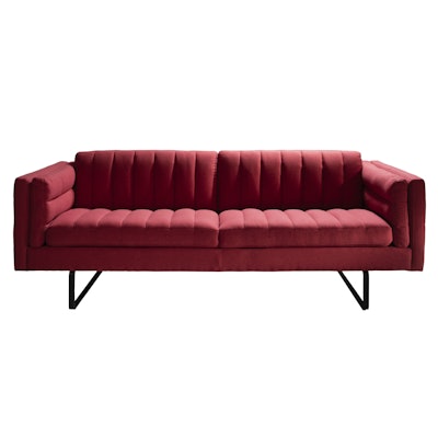 In a midcentury style, the Chandler sofa with cranberry fabric from CORT Events features channel stitching and a black metal base. Pricing is available upon request.