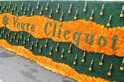 Another step-and-repeat that incorporated on-theme objects was spotted at the ninth annual Veuve Clicquot Polo Classic, held in New York in 2016. The floral wall used greenery to spell out the brand’s name, and surrounded it with orange flowers and real bottles of Champagne.