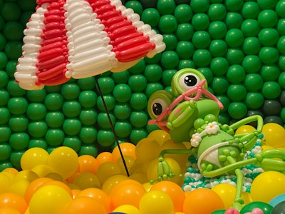A frog was crafted lounging under a striped umbrella while wearing a floral bikini and pink sunglasses.