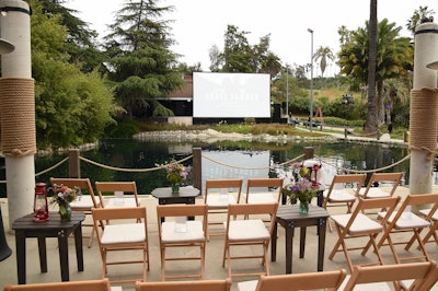 Attendees were seated on a dock as they enjoyed an across-the-water screening at “The Bloom'—a nod to a festival in the show that features bioluminescence in the water. The water at Elysian Park was dressed to replicate the lake from the series, complete with lights that evoked that bioluminescent bloom. “Grace E. Simons Lodge, where we hosted the event, had never done anything of this scale before,” noted Travis, adding that the team worked closely with the LA City Parks team and the fire marshal for all approvals. But the space presented some unique challenges. “When we fell in love with the location, there wasn’t enough room for everyone to sit during the screening,' she explained. 'The solve for that was to build what looked like a 6-foot-tall dock over permanent cement picnic tables that lined one side of the water. No one knew what was under that massive build except us, and it was an elevated, literally and figuratively, viewing experience.”