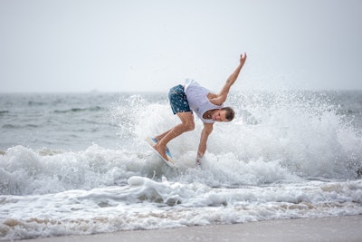 Skimboarding involves gliding on shallow water using a board.