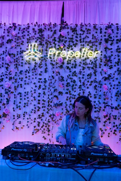 Taylor Bratches treated listeners to a silent disco DJ set at a booth backed by decorative vines and neon Propeller logo signage.
