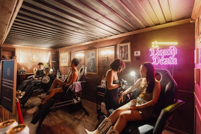 Within the Liquid Death Country Club, guests could get airbrush tattoos at a pop-up studio. The dimly lit space was decorated with wood-paneled walls, golden sconces, and photos in gilded frames. It also had a neon sign advertising the brand name.