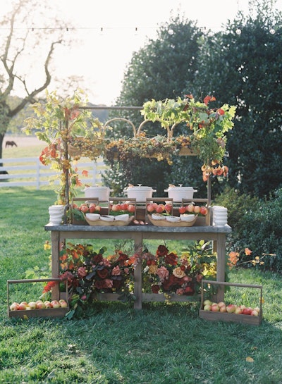 Washington, D.C.-based Ridgewells Catering offers a 'choose-your-own candy apple station' perfect for fall events. Hanging baskets hold fresh seasonal fruit above Dutch ovens filled with molten chocolates and caramels, as well as a variety of toppings laid out for guests to choose from. Ridgewells pre-skewers the apples and plants them inside greenery boxes, providing an interactive experience as guests “pick” their apples before dressing them. (See more fall-focused catering ideas on the Ridgewells blog.)