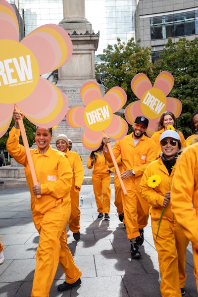 On Oct. 23, meanwhile, pedestrians were gifted foldable umbrellas with The Drew Barrymore Show’s iconic yellow hue by Drew Crews carrying branded logo flowers. And on Nov. 6, the teams will be handing out yellow beanies, scarves, and gloves.