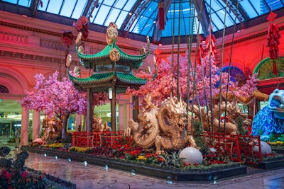 In the East Bed, a tiered pagoda complements a pearl-shaped fountain, surrounded by suspended cloisonné cherry blossom sculptures. Emerald stalks of bamboo stand amid the bright floral landscape. (A popular motif in world art, literature, and philosophy, bamboo is often associated with renewal, vitality, and prosperity, explained the Bellagio team.) Pink and white flowers adorn the branches of the cherry blossom trees, meant to represent a time of renewal and optimism while reminding everyone to appreciate life’s fragility and transience.