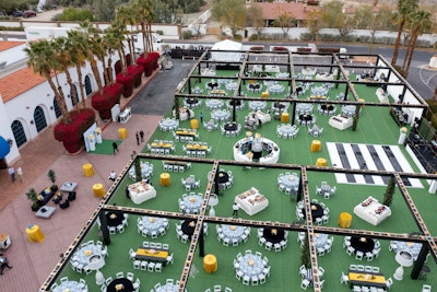 DCi transformed the La Quinta Resort & Club parking lot into an 'Avant Garden' event setting. The parking lot was covered in turf and framed with a custom-fabricated wood structure accented with lighting and greenery. Decor elements and activations included living statues, flower tattoos, cigar rollers, and a live band.
