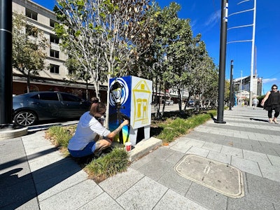Jessica Normington, an artist with Community Visions United, paints the utility box on the Convention Center Boulevard/Julia Street intersection.
