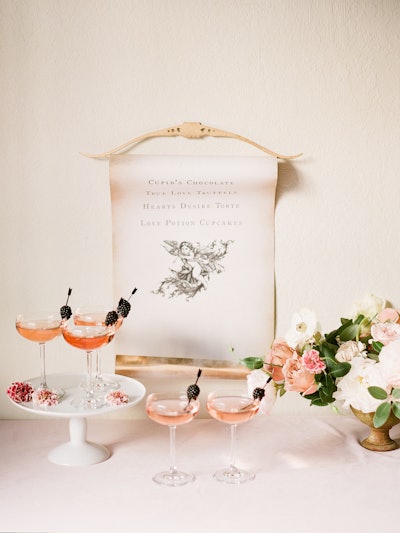 For this welcome drink moment, Glow Events paired Champagne in coupe glasses with blackberries and tiny toothpick arrows. 'First impressions are some of the most important parts of an event,' Glow Events owner and CEO Melanie Zelnick said. As for the cupid scroll made by The Idea Emporium that served as a backdrop: 'We live for the little details.'