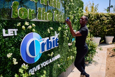 At Interscope and Capital Records' Coachella party, designed and produced by Analog, ORBIT Gum offered attendees refreshing surprises at its 'wall of Enchant-Mint.' Hands reached through a branded hedge to give out gum, fans, and more.