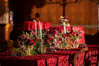 For general guest seating, the event drew inspiration from the King's feast. Twelve-foot-long tables were dressed with candelabras, greenery, and fruit, and the team sourced mismatched Victorian chairs from a prop house. Other seating areas also incorporated Victorian prop furniture, as well as marble tables with ornate arrangements and reserved signs with calligraphy handwritten on old parchment in antique frames.