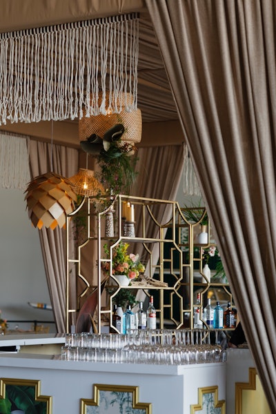 The first thing guests saw upon entering the hangar was this grand central bar complete with pendant lights, leafy prints, and bright florals. 'All good vacations start with a refreshing bevy,' Borunda says.
