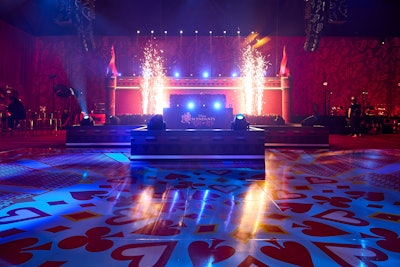 After the screening, guests were led out of the theater by the Queen’s dancing army and into an adjacent soundstage for the after-party, which they entered through 10-foot-tall storybook pages. Entertainment highlights included dancers, a DJ, a Wonderland-inspired dance floor, large castle turret lighting elements, and surprise performances by TwinSauce and Millennium Dance Company featuring pyrotechnics. Every element of the party was inspired by the film, including a multi-tier castle main stage with a rose-clad DJ booth, a main bar with a towering castle back bar featuring family-friendly cocktails and bubbling Merlin’s cauldron, and small bites pulled from the film—including magical cupcakes from the film’s cookbook. For an added fun touch, glam stations offered hair tinsel, face gems, and temporary tattoos.