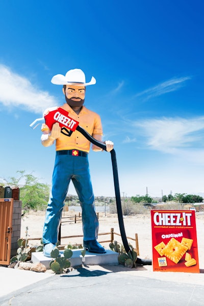 No, that giant Cheez-It you saw on the highway to Joshua Tree in 2023 wasn't a mirage. It was actually a clever promotion from the snack brand, which opened the retro Cheez-It Stop for a week in the Southern California desert. The tongue-in-cheek activation, which was conceived by Weber Shandwick with production by All Terrain, tied into the brand’s newest campaign—playfully named “Want It. Need It. Cheez-It.”—that highlighted the absurd lengths fans will go to fuel up on the snack. In addition to a pop-up shop featuring Cheez-It mementos and exclusive merch, there was a gas pump that pumped Cheez-It bags, plus an oversize muffler man holding a branded Cheez-It pump to draw attention from passersby. See more: Gas Prices Too High? This Service Station Pumps Cheez-Its Instead