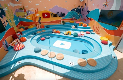 At Coachella 2022, the YouTube Artist Lounge featured a fun seating area inspired by the YouTube logo—complete with bright and colorful pillows and desert-inspired wall decor. It was designed and produced by MAS. See more: Coachella 2022: Peek Inside the Festival's Buzziest Parties & Brand Activations
