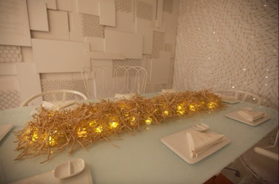At DIFFA Chicago’s Dining by Design in November 2013, the Coalesse table, designed by Gensler, had subtle twinkle lights and a wishbone pattern swirling on its walls. The table's centerpiece was a dense arrangement of wishbones, laid over a row of softly glowing electric candles.