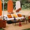 This seating area, courtesy of planner Jade & Joy Events, includes the white midcentury sofa ($375), rust orange swivel chair set ($250), large jute rug ($175), and slatted midcentury coffee table ($90), available from Something Vintage.