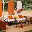 This seating area, courtesy of planner Jade & Joy Events, includes the white midcentury sofa ($375), rust orange swivel chair set ($250), large jute rug ($175), and slatted midcentury coffee table ($90), available from Something Vintage.