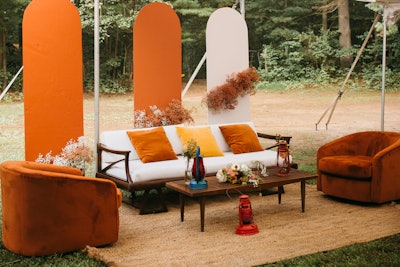 This seating area, courtesy of planner Jade & Joy Events, includes the white midcentury sofa ($375), rust orange swivel chair set ($250), large jute rug ($175), and slatted midcentury coffee table ($90), available from Something Vintage.