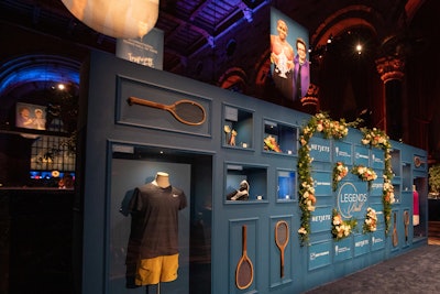 An interactive step-and-repeat was a custom-built wall spotlighting museum artifacts from the Hall of Fame collection, complete with built-in lighting and protective plexiglass. The nine displayed items included Olympic gold medals; shoes worn by Serena Williams, Roger Federer, and Coco Gauff; and the Presidents Cup awarded to John McEnroe for winning Gentlemen’s Singles at the 1983 Wimbledon Championships.