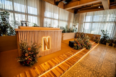 Because the hero moment of the evening was a toast, westhaus opted to fabricate a custom stage made of clad beige wood with a sisal carpet top and downlit wood-finished steps.