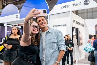 An attendee poses with Mario Dedivanovic of MAKEUP BY MARIO.